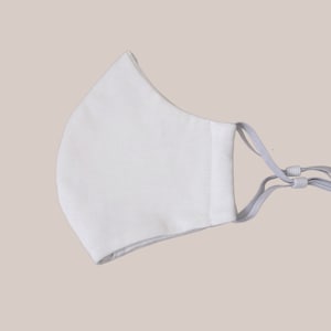 May include: A white face mask with gray elastic ear loops. The mask is made of a soft, breathable fabric.