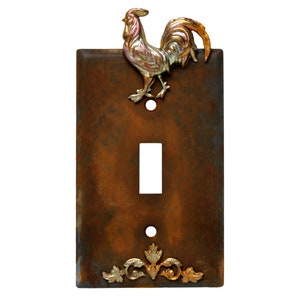 May include: A rustic brown light switch cover with a gold rooster design and gold leaf accents.
