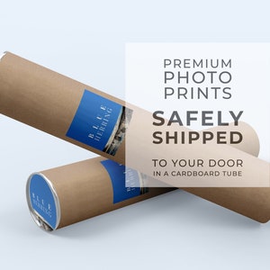 May include: Two brown cardboard tubes with silver caps. The tubes are stacked on top of each other. The top tube has a blue label with the text "BLUE HERRING" on it. The text "PREMIUM PHOTO PRINTS SAFELY SHIPPED TO YOUR DOOR IN A CARDBOARD TUBE" is in white text on a white background.