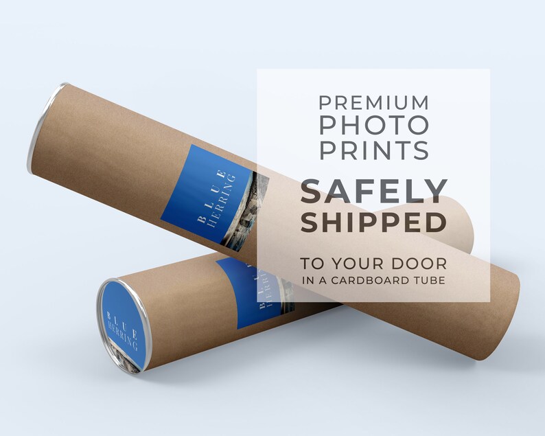 May include: Two brown cardboard tubes with silver caps. The tubes are stacked on top of each other. The top tube has a blue label with the text "BLUE HERRING" on it. The text "PREMIUM PHOTO PRINTS SAFELY SHIPPED TO YOUR DOOR IN A CARDBOARD TUBE" is in white text on a white background.