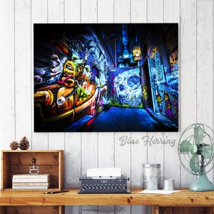 May include: A colorful graffiti alleyway with vibrant blue, yellow, green, and red paint. The alleyway is narrow and the walls are covered in graffiti art. The image is taken from a low angle, looking up at the walls.
