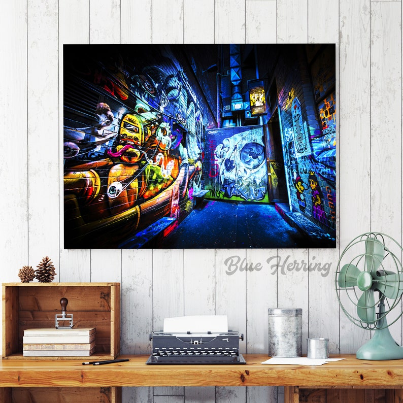 May include: A colorful graffiti alleyway with vibrant blue, yellow, green, and red paint. The alleyway is narrow and the walls are covered in graffiti art. The image is taken from a low angle, looking up at the walls.