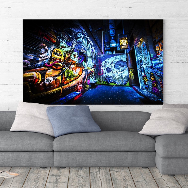 May include: A dark alleyway with colorful graffiti art on the walls. The art features a skull, a cartoon character, and other abstract designs. The alleyway is lit with blue and purple lights.