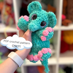 May include: A crochet pattern for a teal blue elephant amigurumi toy with pink accents. The elephant has large, glittery eyes and a long trunk.  PDF crochet pattern only.