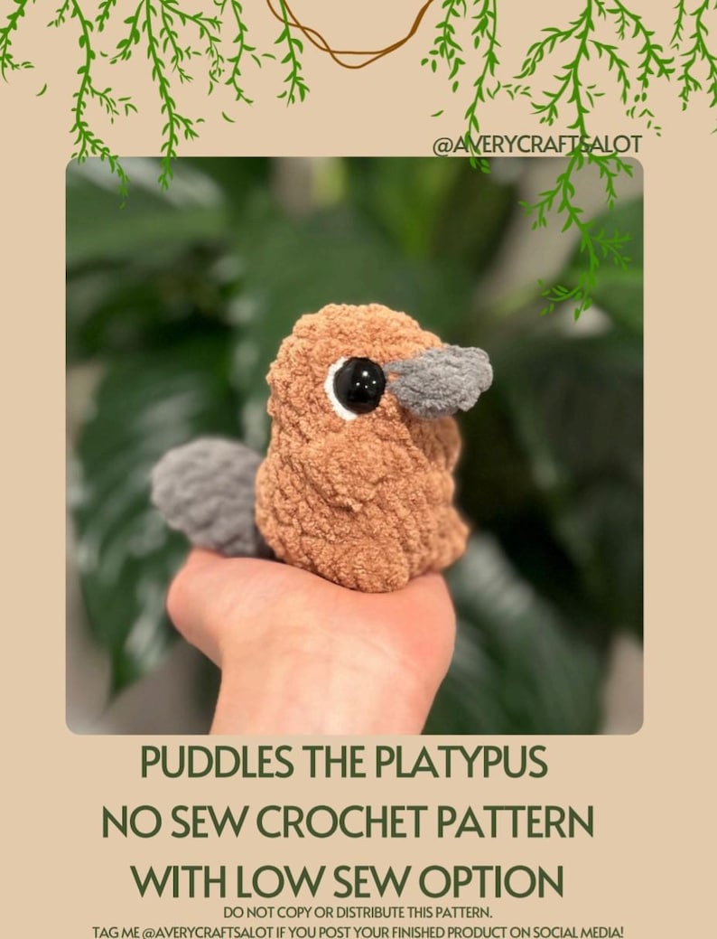 May include: A crocheted platypus toy with brown and gray fur. The toy is being held in a hand. The text "Puddles the Platypus No Sew Crochet Pattern with Low Sew Option" is at the bottom of the image.