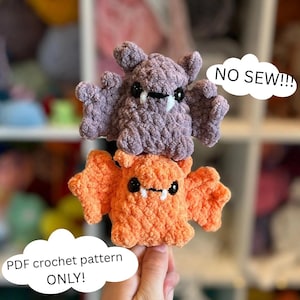 May include: Two crocheted bat plushies, one purple and one orange, with black eyes and white fangs. The purple bat is on top of the orange bat. Text on the image says "NO SEW!!!" and "PDF crochet pattern ONLY!"
