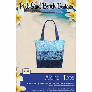 May include: A tote bag with a blue and white floral pattern, featuring a dark blue handle and base. The bag is labeled "Aloha Tote" with the text "6 POCKETS INSIDE • FAT QUARTER FRIENDLY". The brand name "Pink Sand Beach Designs" is at the top.