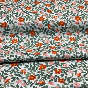K&ouml;nnte beinhalten: Wei&szlig;er Stoff mit einem sich wiederholenden Muster aus orangefarbenen und rosa Bl&uuml;ten, gr&uuml;nen Bl&auml;ttern und kleinen braunen Schmetterlingen.