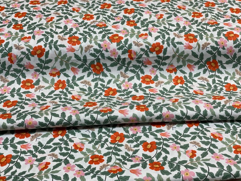 K&ouml;nnte beinhalten: Wei&szlig;er Stoff mit einem sich wiederholenden Muster aus orangefarbenen und rosa Bl&uuml;ten, gr&uuml;nen Bl&auml;ttern und kleinen braunen Schmetterlingen.