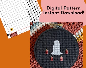 Puede incluir: Un patrón de punto de cruz en blanco y negro de un fantasma con cuatro velas rojas sobre un fondo negro. El patrón está en un aro de bordado redondo. El texto "Digital Pattern Instant Download!" está en texto rosa sobre un fondo rosa claro.