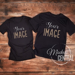 May include: Two black t-shirts laid flat on a wooden surface. The t-shirts have the text "Your Image" printed on them.