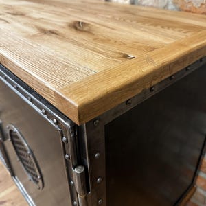 May include: A black metal cabinet with a wood top. The cabinet has a metal door with a hinge and a metal handle. The cabinet is decorated with metal rivets.