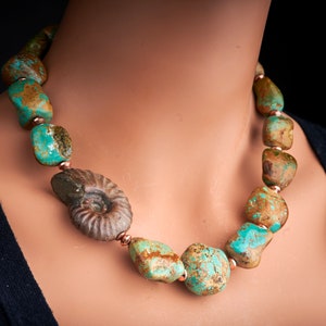 May include: A turquoise and brown stone necklace with a fossilised ammonite pendant. The necklace is made of large, irregular shaped stones with copper accents.