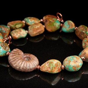 May include: A turquoise and copper necklace with a fossilised ammonite pendant. The necklace features irregularly shaped turquoise stones with brown and green marbling.