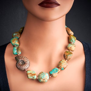 May include: A turquoise and brown stone necklace with a fossilised ammonite pendant. The necklace is made of large, irregular shaped stones and is strung on a copper wire.