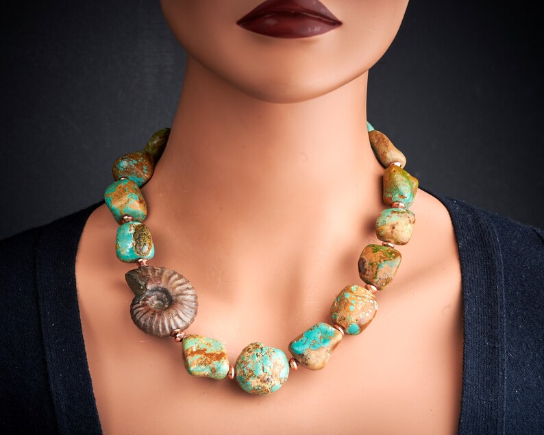 May include: A turquoise and brown stone necklace with a fossilised ammonite pendant. The necklace is made of large, irregular shaped stones and is strung on a copper wire.
