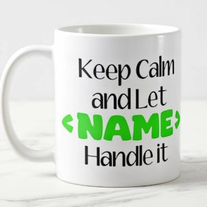 May include: White ceramic mug with a curved handle. The mug features the text "Keep Calm and Let NAME Handle it" in black, with "NAME" in bright green. The mug is designed for beverages.