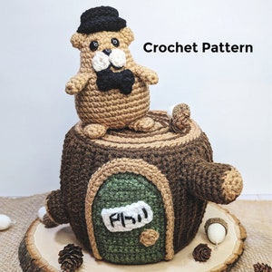 May include: Crochet pattern for a brown and green tree stump house with a small brown bear wearing a black hat and bow tie sitting on top. The house has a green door with a white sign that says "P.W.W."