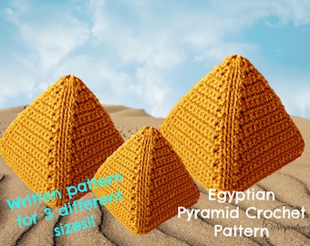 May include: Three crocheted pyramids in varying sizes, displayed on a sandy surface with a blue sky background. The pyramids are a warm golden-yellow color. Text on the image reads "Written pattern for 3 different sizes!!" and "Egyptian Pyramid Crochet Pattern".