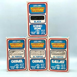 Puede incluir: Una colección de cajas de materiales de jardinería "Life-Like" vintage. Las cajas son blancas con detalles azules y rojos, y presentan textos como "Black Scenic Stone", "Gravel" y "Ballast". Cada caja contiene un tipo diferente de material.