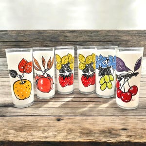 Six  glass tumblers with colorful fruit illustrations. The glasses have a white background with black outlines and feature cherries, grapes, apples, and leaves in shades of red, orange, yellow, green, purple, and black.