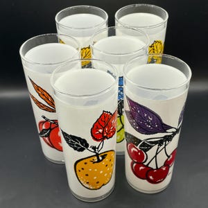 Six  glass tumblers with colorful fruit illustrations. The glasses have a white background with black outlines and feature cherries, grapes, apples, and leaves in shades of red, orange, yellow, green, purple, and black.