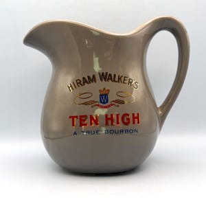 Pode incluir: Jarro de cerâmica castanho com bico curvo e pega grande. O jarro apresenta o texto "Hiram Walker's TEN HIGH A TRUE BOURBON" em letras douradas e vermelhas, com um pequeno emblema.