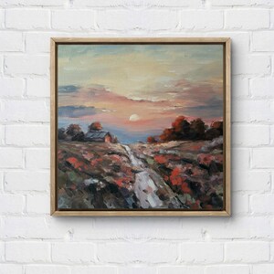 May include: Oil painting of a landscape scene with a sunset. The artwork features a small building, a path, and trees in shades of red, orange, and green. The sky has pink, orange, and blue hues, and the painting is framed in a wooden frame.