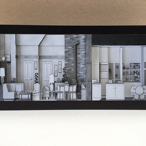 Puede incluir: Un diorama enmarcado en negro que representa el interior de una sala de estar y una cocina. La sala de estar cuenta con un sofá, dos sillas, una mesa de café y una lámpara. La cocina cuenta con una encimera, gabinetes y un refrigerador. El diorama está hecho de papel y está detallado con texturas realistas.