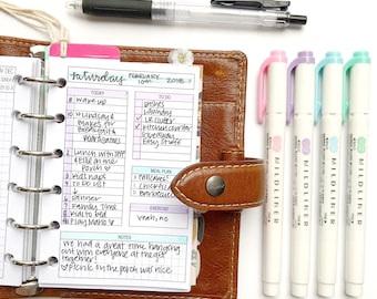 May include: A close-up of a brown leather planner with a weekly schedule for Saturday, February 10th, 2018. The planner is open to the daily schedule, which includes a to-do list, meal plan, and notes section. The planner is surrounded by four colorful highlighters.