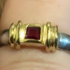 Può includere: Un anello in oro e argento con una pietra preziosa rossa quadrata al centro.