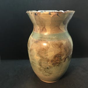 May include: A handcrafted ceramic vase with a wide, scalloped rim. The vase displays a mix of earthy hues, such as brown, green, and tan, with a textured finish. The design has a rustic, organic feel, suitable for home decor.