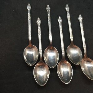 May include: Set of six silver spoons with ornate handles. The spoons have a classic design and are perfect for serving tea or coffee.