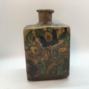 May include: A square ceramic vase with a narrow neck and a floral design in shades of blue, green, yellow, and red.