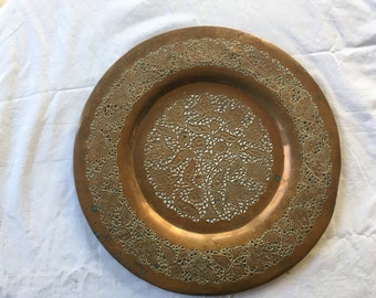 Könnte beinhalten: Ein rundes Serviertablett aus Kupfer mit filigranen floralen Designs, die an den Rändern und in der Mitte ausgeschnitten sind. Das Tablett hat eine warme, gealterte Patina.