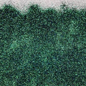 Puede incluir: Primer plano de una purpurina verde con un acabado iridiscente brillante. La purpurina es fina y tiene una textura densa.