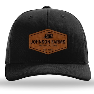 May include: Black trucker hat with a brown leather patch that says "JOHNSON FARMS, SMITHVILLE, TEXAS, EST. 1964" and a tractor silhouette.