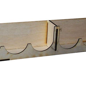 May include: Wooden wall mount organizer with six slots for storing paint tubes. The organizer is made of light brown wood and has a black trim. It is labeled "Made in the USA" with a small American flag.