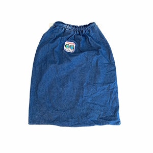May include: A blue denim skirt with a drawstring waist and a small patch with a logo on the front.