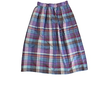 May include: A purple, blue, and white plaid skirt with a button closure at the waist.