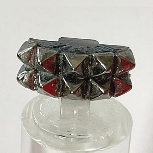 Op de afbeelding: Een zilveren ring met een geometrisch ontwerp. De ring is gemaakt van meerdere kleine, puntige vormen die een textuur creëren.