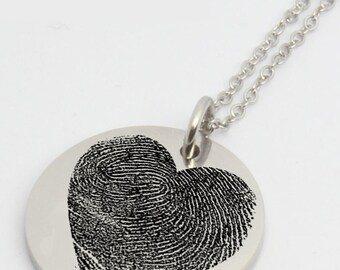 May include: A silver necklace with a round pendant featuring a black fingerprint design in the shape of a heart.