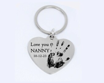 May include: Silver heart-shaped keychain with a handprint and the text "Love you NANNY 10-12-23".