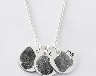 May include: Silver necklace with three round pendants. Two pendants feature fingerprint designs, and the third pendant has the word "Mom" inscribed on it.