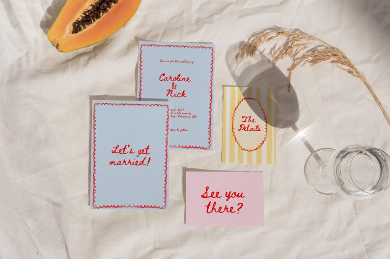 May include: Wedding invitation suite with blue and white cards with red lettering. The cards say "Let's get married!" and "Caroline & Nick". There is also a pink card that says "See you there?" and a yellow and white striped card that says "The Details".