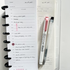 Op de afbeelding: Een open planner met een schema voor 12 november 2025 en een focusgedeelte voor 4 november 2025. Een roze markeerstift markeert een tijdvak. Een roze en een zwarte pen liggen naast de planner.