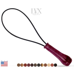 May include: A wooden handle with a black leather loop attached. The handle is a deep burgundy color and has a smooth finish. The loop is made of a durable leather and is designed to be used for pulling or lifting objects.  LVX Supply & Co.