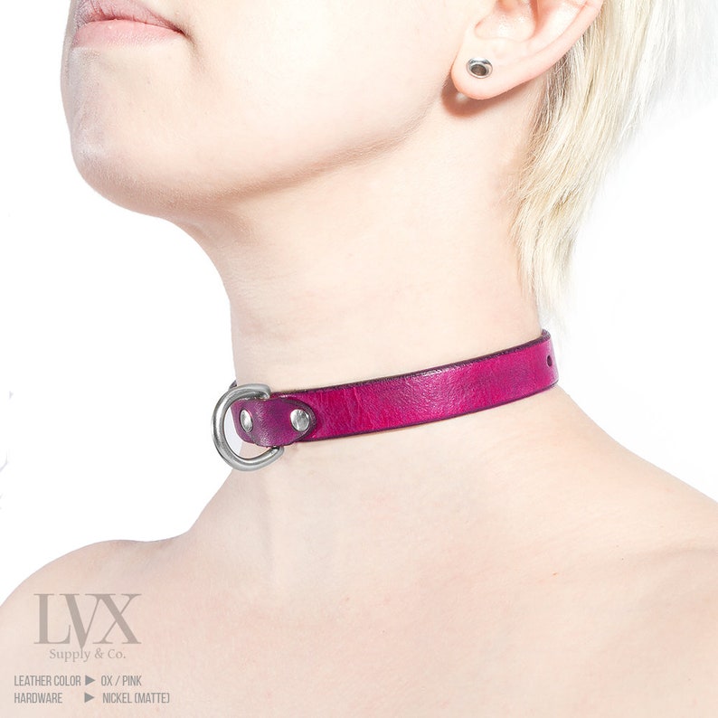 Pode incluir: Um colar de couro rosa com um anel de metal prateado e dois tachas prateadas. O texto "LVX Supply & Co." &eacute; impresso na parte inferior da imagem. O texto "Leather Color: OX / PINK" e "Hardware: Nickel (MATTE)" tamb&eacute;m &eacute; impresso na parte inferior da imagem.