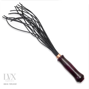 May include: A black leather whip with a purple heartwood handle. The whip has multiple strands and a copper accent at the base of the handle.