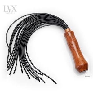 May include: A black leather whip with a wooden handle. The handle is made of bubinga wood and has a copper ferrule. The whip has multiple strands of leather.
